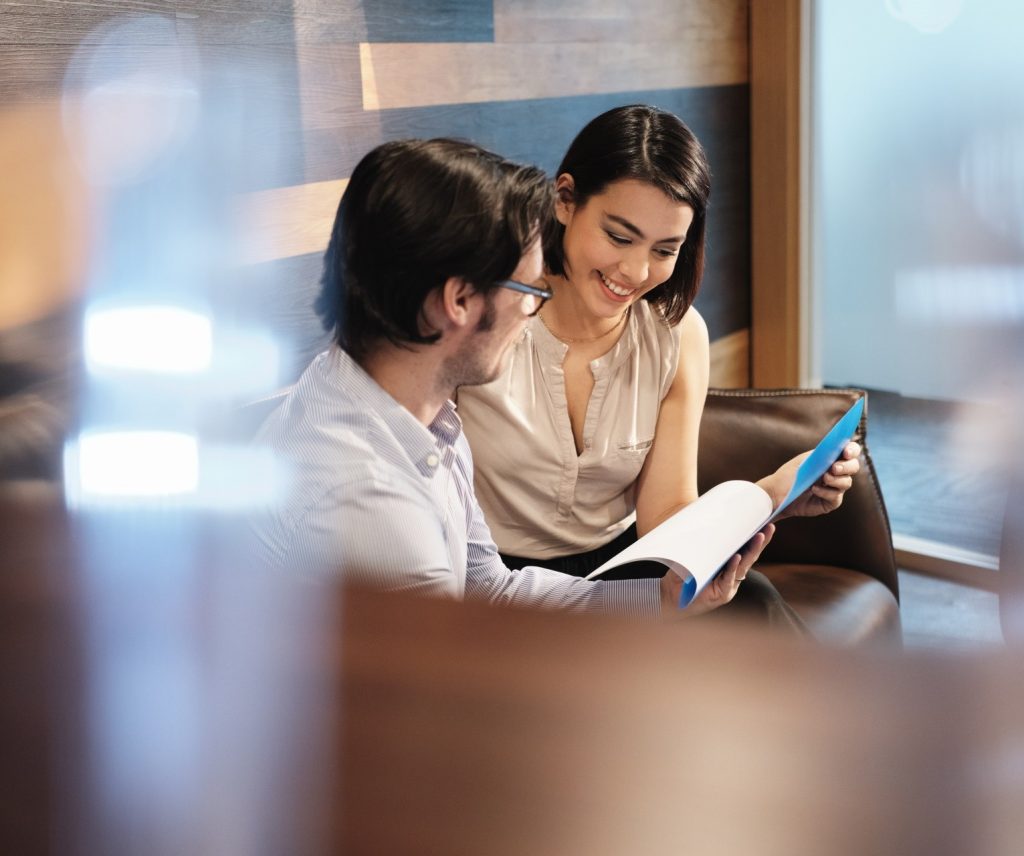 man and women sitting on sofa and looking at papers